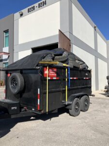 A branded MGM Household Services junk removal trailer loaded with old tires in Las Vegas, NV.
