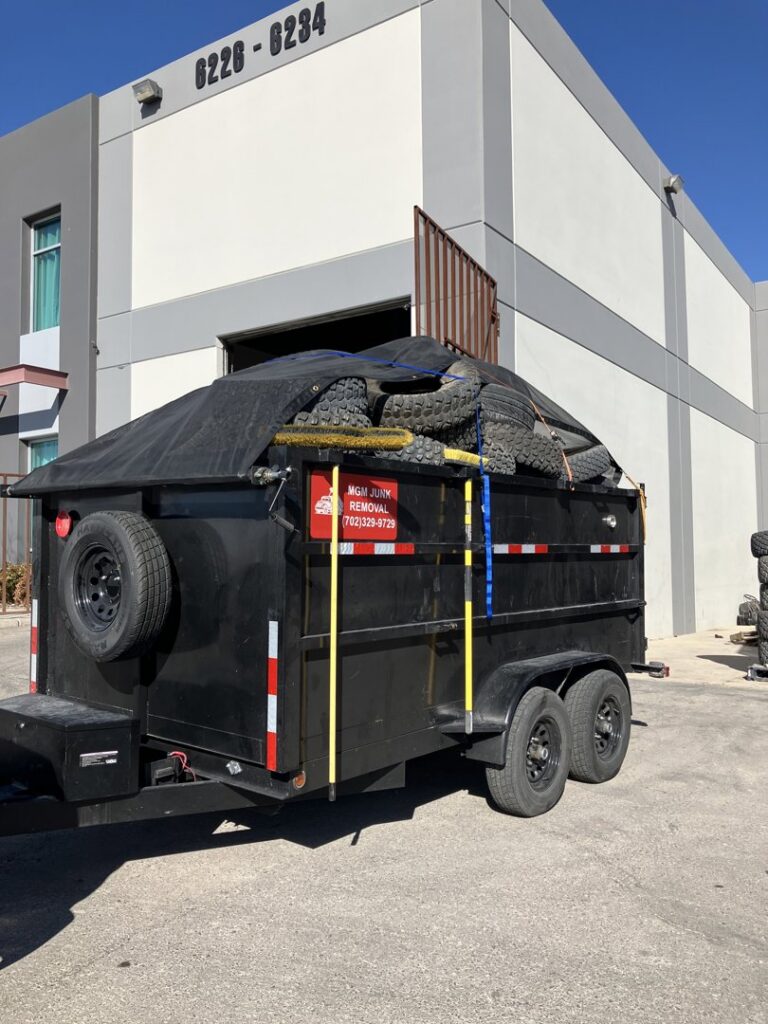 A branded MGM Household Services junk removal trailer loaded with old tires in Las Vegas, NV.