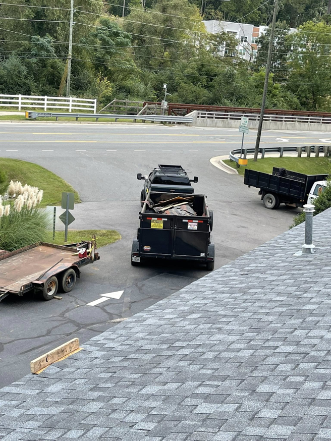 A truck towing a dump trailer filled with debris for The Dump Bros LLC on a road in Raleigh, NC.