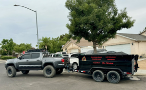 A Wasted Junk Removal truck pulling a loaded trailer with junk covered by a tarp in Corona, CA.
