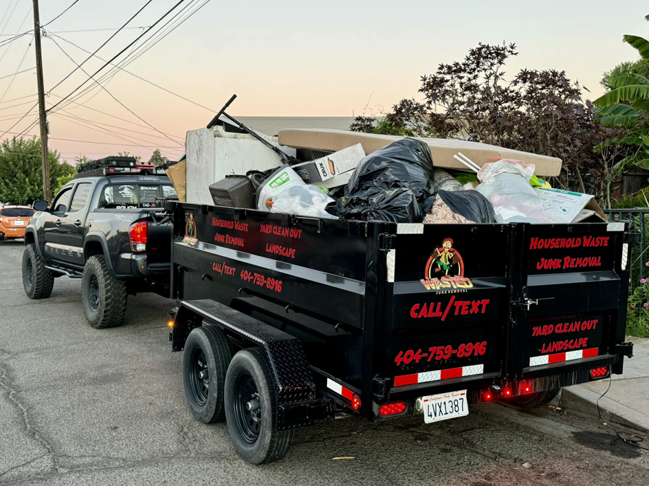 A Wasted Junk Removal truck and trailer fully loaded with household waste and debris after a job in Corona, CA.