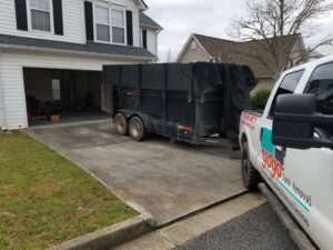 A GoGo Junk Removal truck and trailer parked at a residential garage cleanout job in Atlanta, GA.