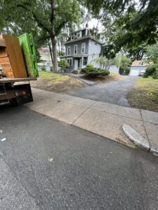 A Junkluggers truck parked on a residential street with items loaded, performing junk removal in Hicksville, NY.