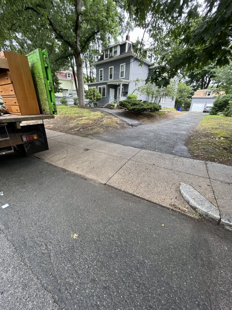 A Junkluggers truck parked on a residential street with items loaded, performing junk removal in Hicksville, NY.