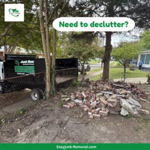 A junk removal truck parked next to a large pile of bricks and concrete debris for pickup by Easy junk removal in Newport News, VA.