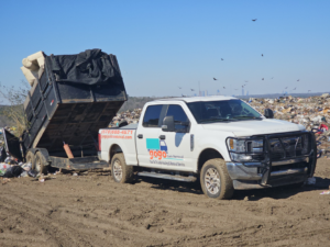 A GoGo Junk Removal truck and trailer dumping a load of junk at a landfill in Atlanta, GA.