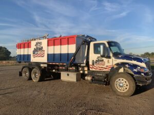A Bragg About This Dump junk removal truck with a roll-off dumpster on a job site in Columbus, OH.