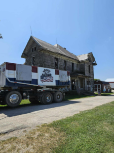 A Bragg About This Dump junk removal truck with a roll-off dumpster parked at a dilapidated house in Columbus, OH.