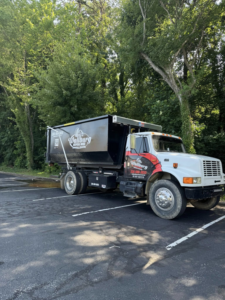 A Wallburg Disposal Worx LLC junk removal truck with a black dumpster parked in High Point, NC.