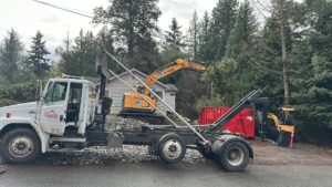 A Cascade Container and Recycling truck with an excavator and red dumpster at a junk removal site in Seattle, WA.