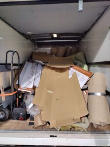 The interior of a junk removal truck filled with rolled carpets, cardboard, and other debris by One Call Junk Removal in Minneapolis, MN
