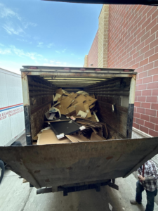 A Fish Junk Removal And Trash Out Services LLC truck loaded with cardboard boxes and debris in Janesville, WI.