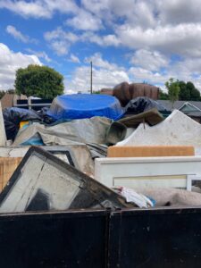 A junk removal truck completely full of various debris, including a blue kiddie pool, ready for disposal by Larry The Rubbish Man in Los Angeles, CA.