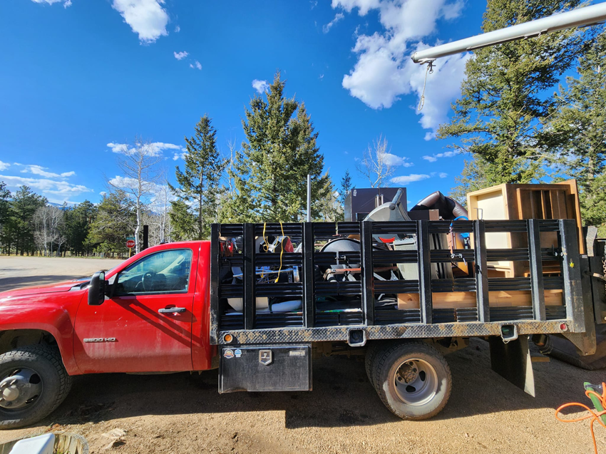 A red junk removal truck loaded with various household items and debris by Bear Foot Junk Removal in Bailey, CO.
