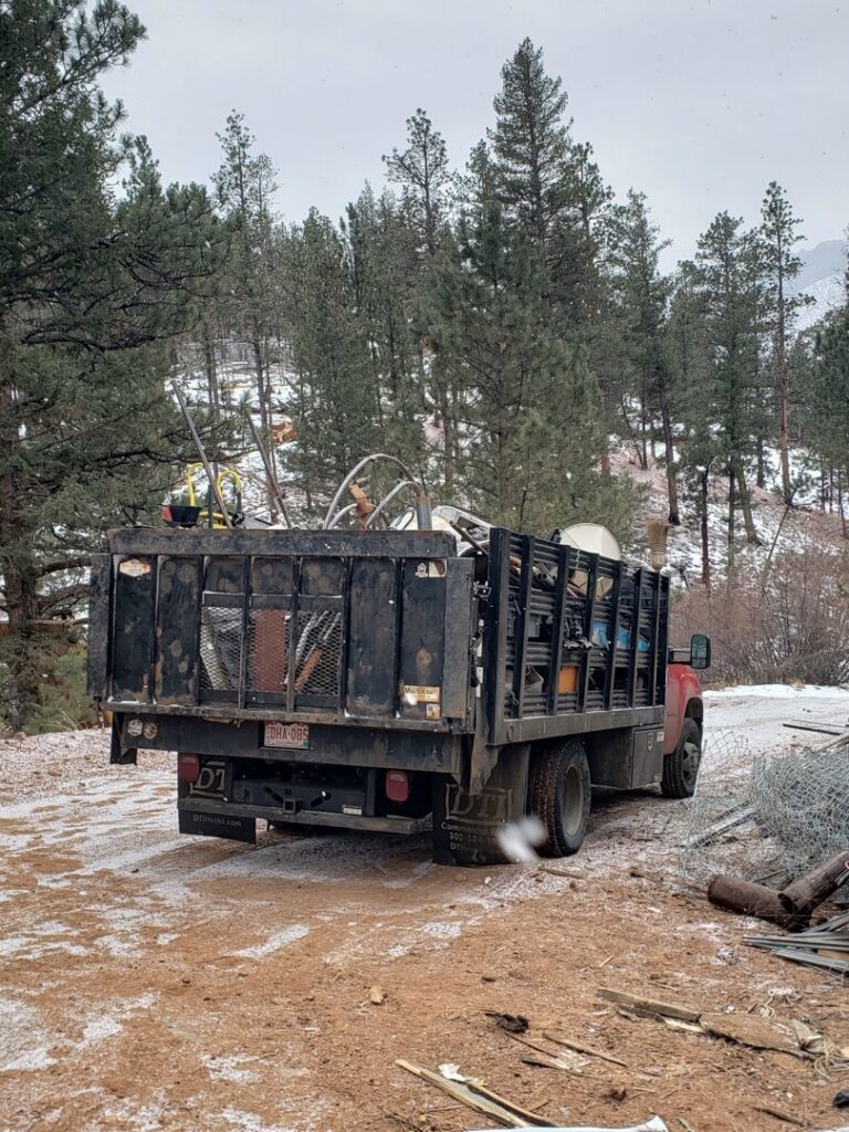 A red junk removal truck loaded with metal items and debris by Bear Foot Junk Removal in Bailey, CO.