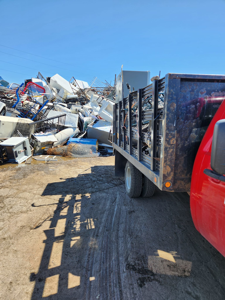 A junk removal truck full of scrap metal and appliances at a disposal site by Bear Foot Junk Removal in Bailey, CO.