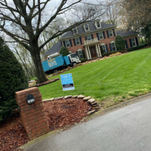 A Stand Up Guys Junk Removal truck parked on the street at a large residential property in Nashville, TN.