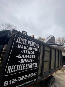 A Hoosier Outdoor Services junk removal truck loaded with old furniture and trash bags in Bloomington, IN.