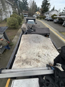 A junk removal truck loaded with a mattress and various furniture items, ready for disposal by All City Junk Removal in Kent, WA.