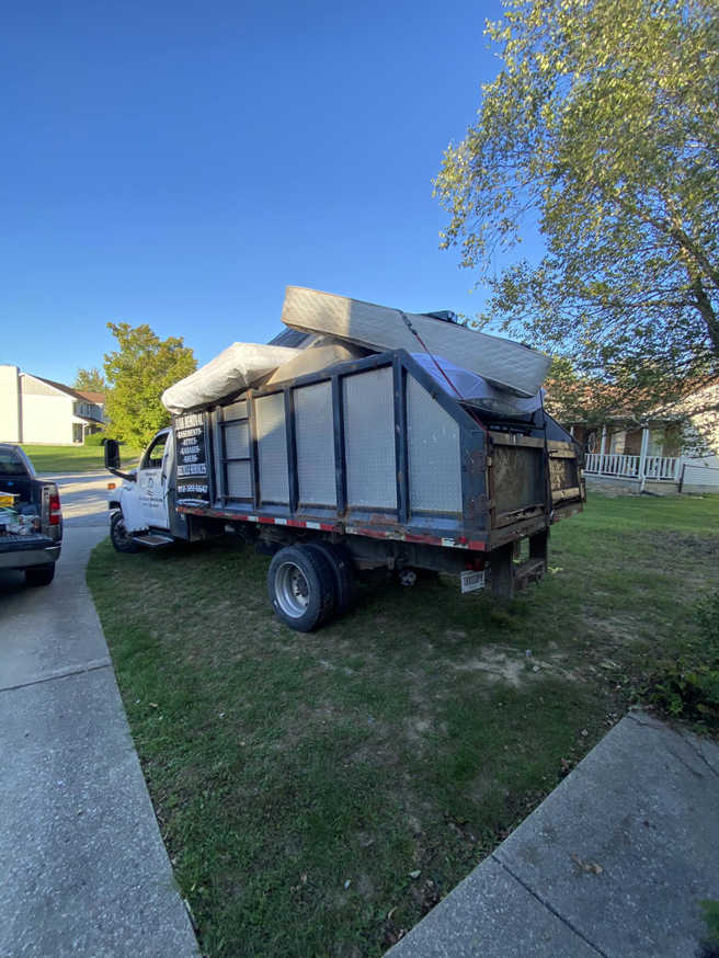 A Hoosier Outdoor Services junk removal truck loaded with mattresses and debris in Bloomington, IN.