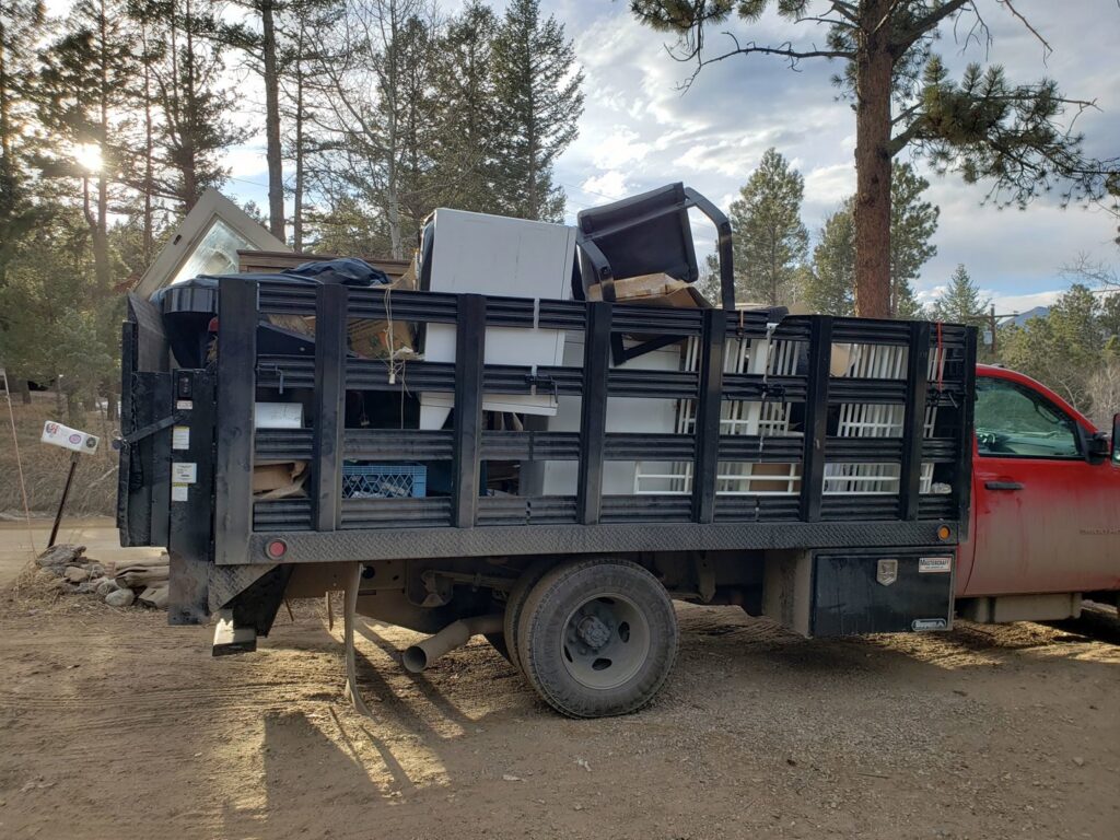 A red junk removal truck loaded with appliances and other items by Bear Foot Junk Removal in Bailey, CO.