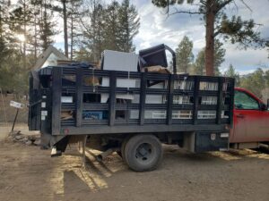 A red junk removal truck loaded with appliances and other items by Bear Foot Junk Removal in Bailey, CO.