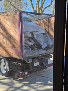 A junk removal truck from 402 Junk Removal in Lincoln, NE, loaded with rolled-up carpet and construction debris.