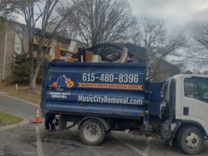A Music City Removal truck loaded with furniture and debris parked outside an apartment building in Nashville, TN.