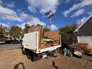 A Republic Junk Removal truck is loaded with wood, pallets, and various debris at a job site in San Diego, CA.