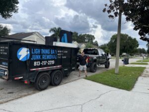 A Lightning Bay Junk Removal truck and trailer loaded with furniture and a mattress, ready for transport in Tampa, FL.