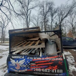 The back of a Merica JunkBoss LLC truck loaded with wooden pallets and various debris, indicating a completed junk removal job in Hammond, IN.
