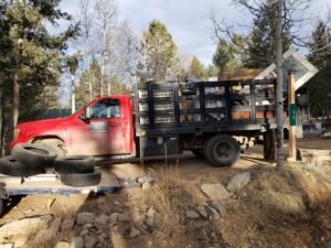 A red junk removal truck loaded with tires, windows, and other debris by Bear Foot Junk Removal in Bailey, CO.