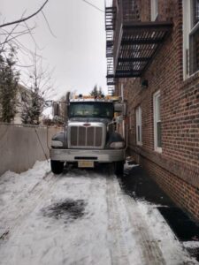 A Champion Waste Removal, Inc. truck parked in a snowy alleyway next to a brick building in Orange, NJ.