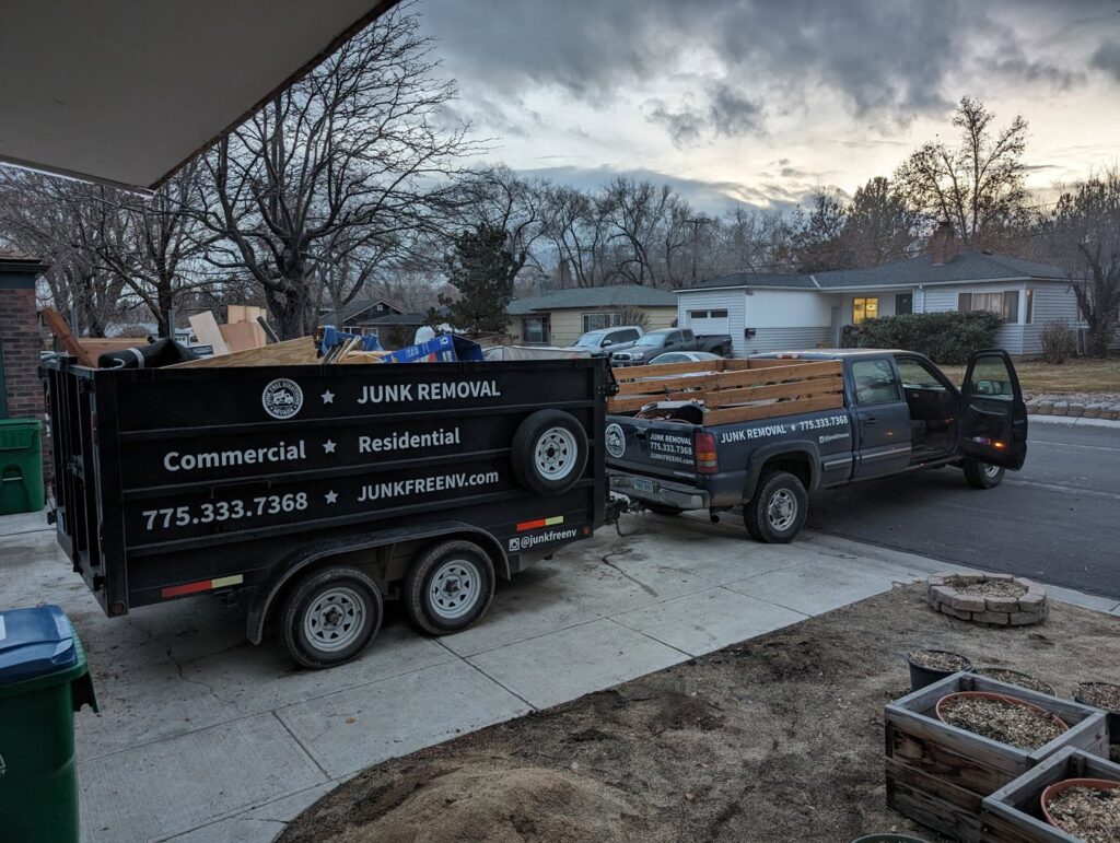 A Junk Free Solutions truck and trailer loaded with wood and debris in a residential driveway in Reno, NV.