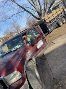 A red junk removal truck with a loaded trailer, operated by Property Solutions & Junk Removal LLC in East Peoria, IL.