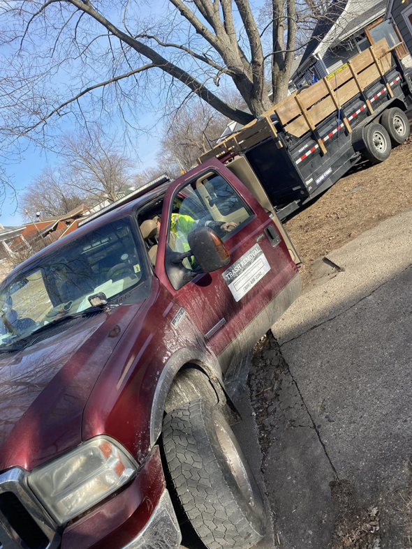 A red junk removal truck with a loaded trailer, operated by Property Solutions & Junk Removal LLC in East Peoria, IL.