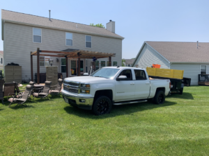 A Jack My Junk truck and dump trailer parked at a residential property for junk removal services in St. Charles, MO.