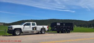A Clean Sweep Junk Removal truck and dump trailer parked on a roadside, ready for a job in Augusta, ME.
