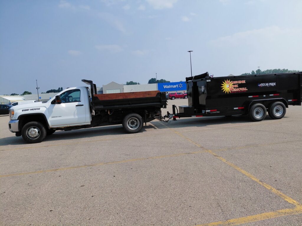 A white pickup truck pulling a black dump trailer with the Sunshine Junk Removal LLC logo in Lake City, MN.