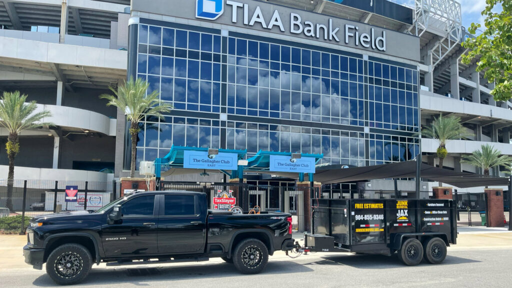 Junk Removal JAX truck and trailer parked outside TIAA Bank Field in Jacksonville, FL, ready for service.
