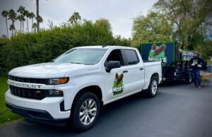 A Mora's Junk Removal & Hauling llc. truck and trailer with a worker giving a thumbs up in Scottsdale, AZ