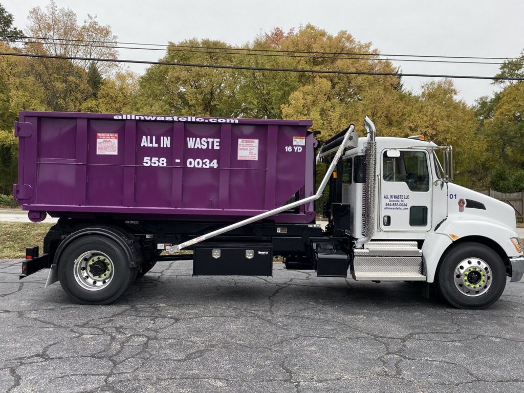 An All In Waste junk removal truck with a purple dumpster loaded on the back, ready for service in Greenville, SC.