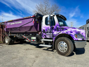 A JP's Disposal Inc. junk removal truck with a purple dumpster on its back, parked in Hampton, VA.