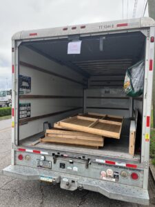 A junk removal truck with a 'Junk Removal' sign and wooden panels inside, operated by LP Junk Removal in Birmingham, AL.