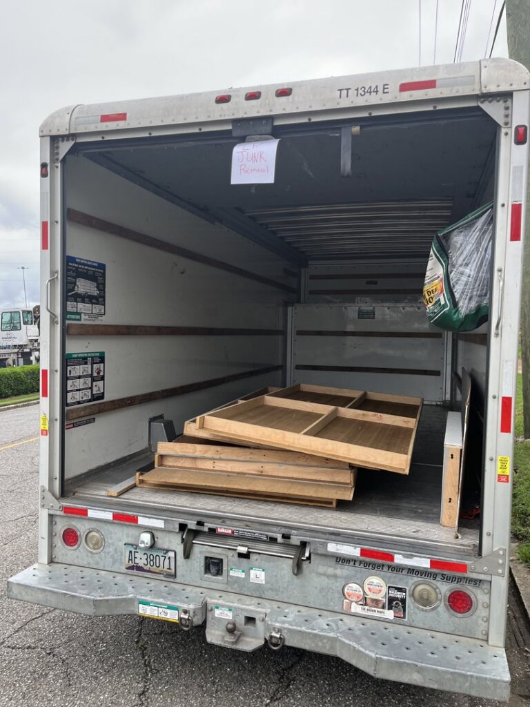 A junk removal truck with a 'Junk Removal' sign and wooden panels inside, operated by LP Junk Removal in Birmingham, AL.