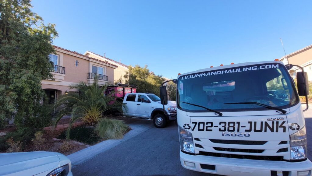 Branded junk removal trucks from Las Vegas Hauling Junk & Moving parked at a residential job site in Las Vegas, NV