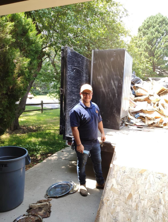 A Super Junkers worker standing by a truck loaded with a refrigerator and other junk in Denver, CO