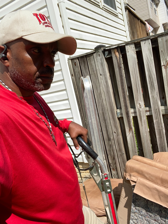 A Total Junk and Bulk Disposal worker in Whitsett, NC, holding a dolly, ready to remove items