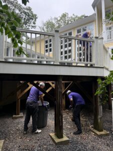 Junk Runners LLC crew members performing a cleanup and junk removal service under a residential deck in Fairfax, VA.