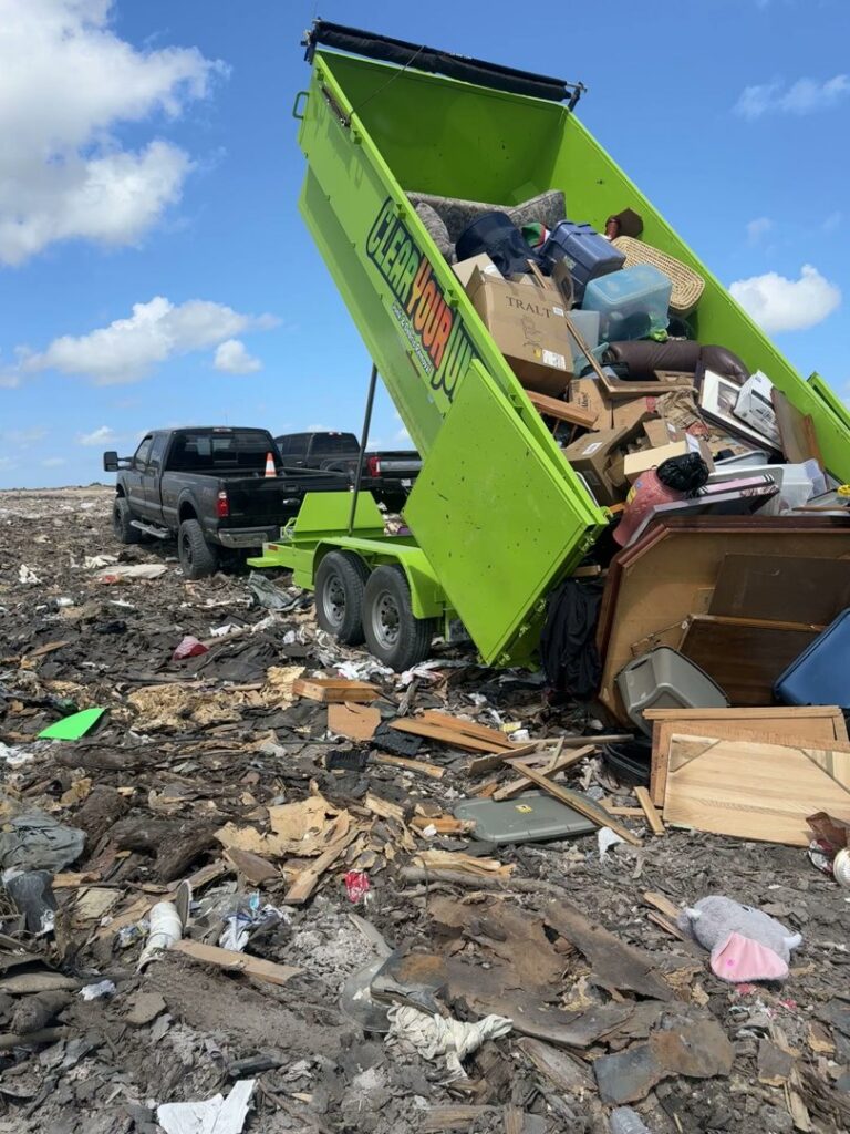A Clear Your Junk - Pearland, Houston, TX trailer dumping a large load of debris at a disposal site.
